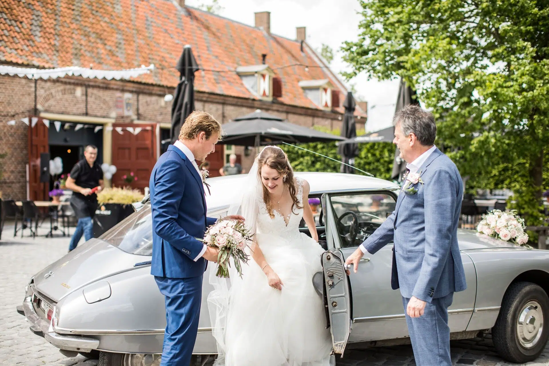 Bruidspaar komt aan in een oude auto op hun bruiloft bij Kasteel Ammersoyen