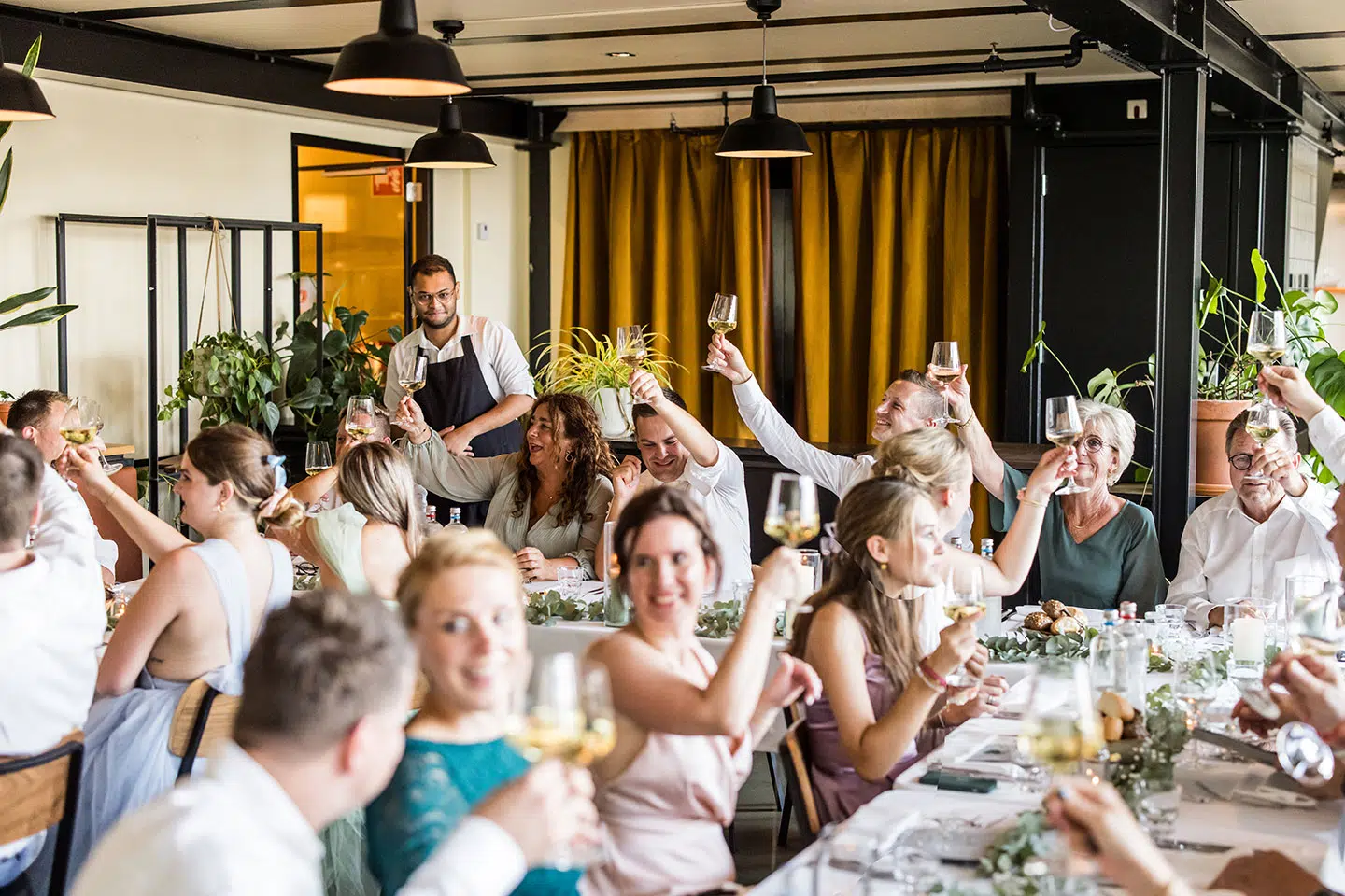 Bruidspaar proost met gasten tijdens hun bruiloft bij Dudok aan de Maas