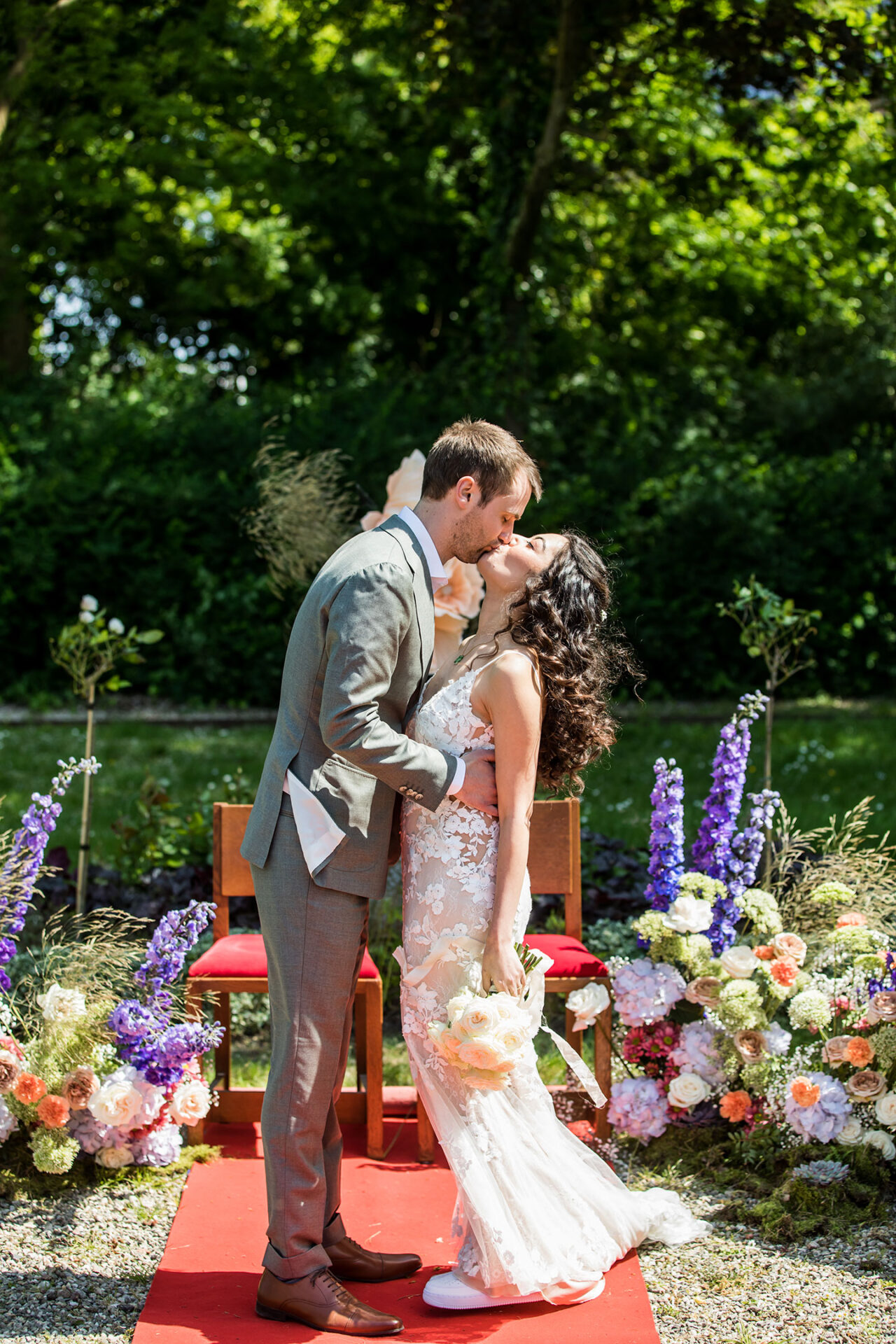 Bruidspaar kust elkaar omringd door kleurrijke bloemen
