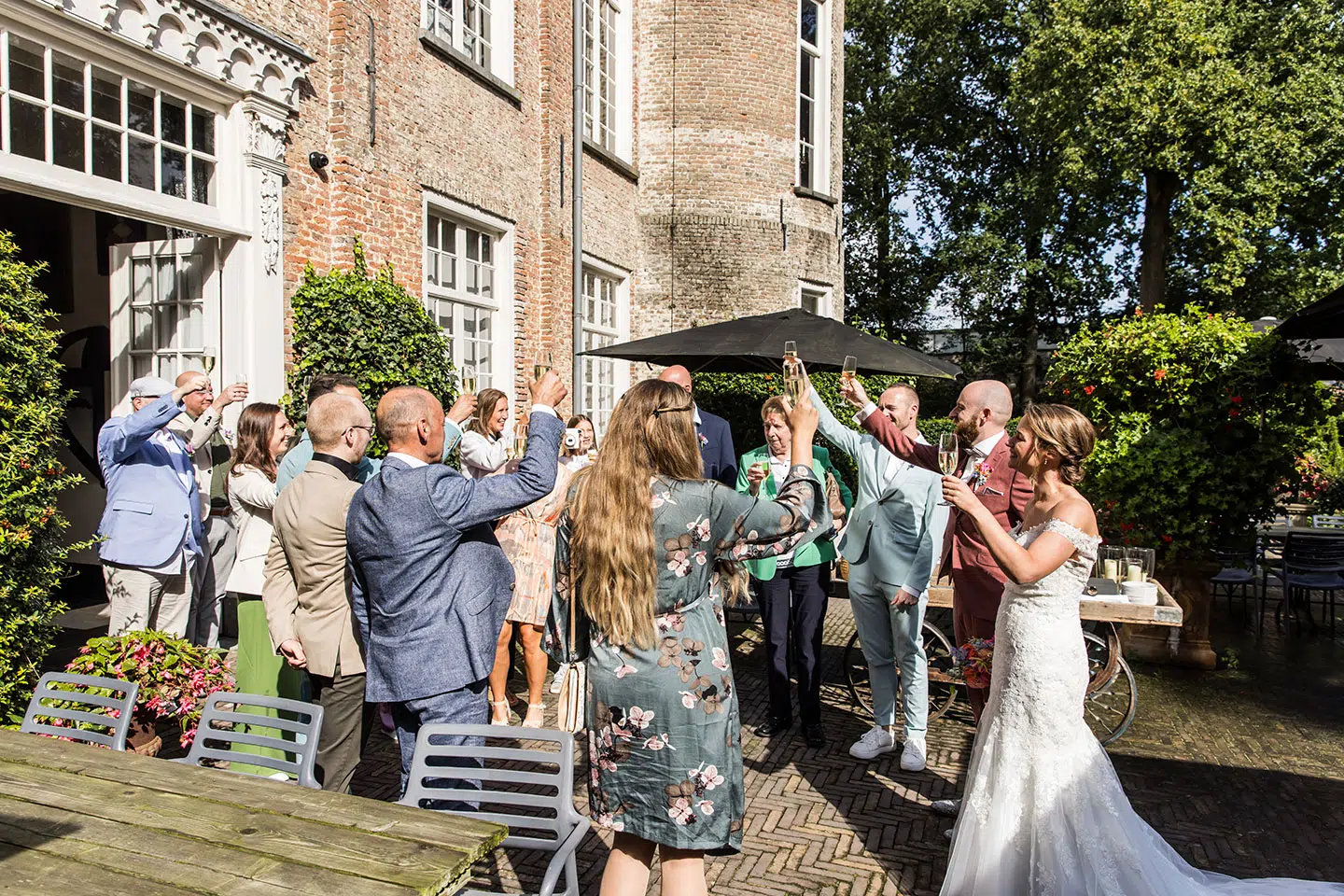 Bruidspaar proost met vrienden en familie tijdens bruiloft bij Kasteel Henkenshage