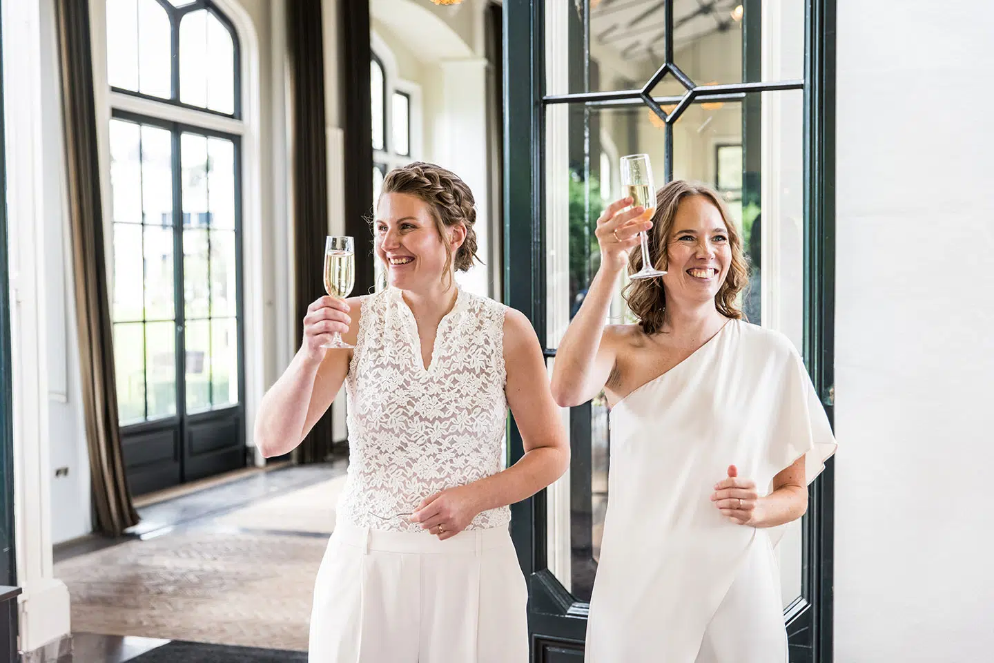 Twee bruiden proosten met hun gasten tijdens een bruiloft