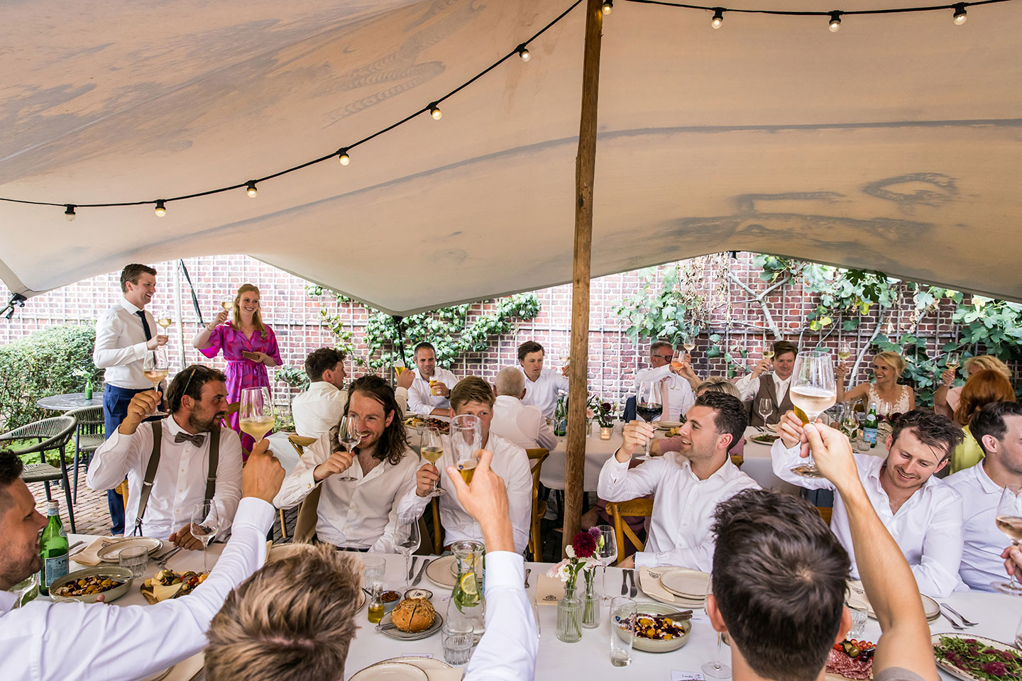 Gasten proosten op bruidspaar onder een tent bij Kasteel Geldrop