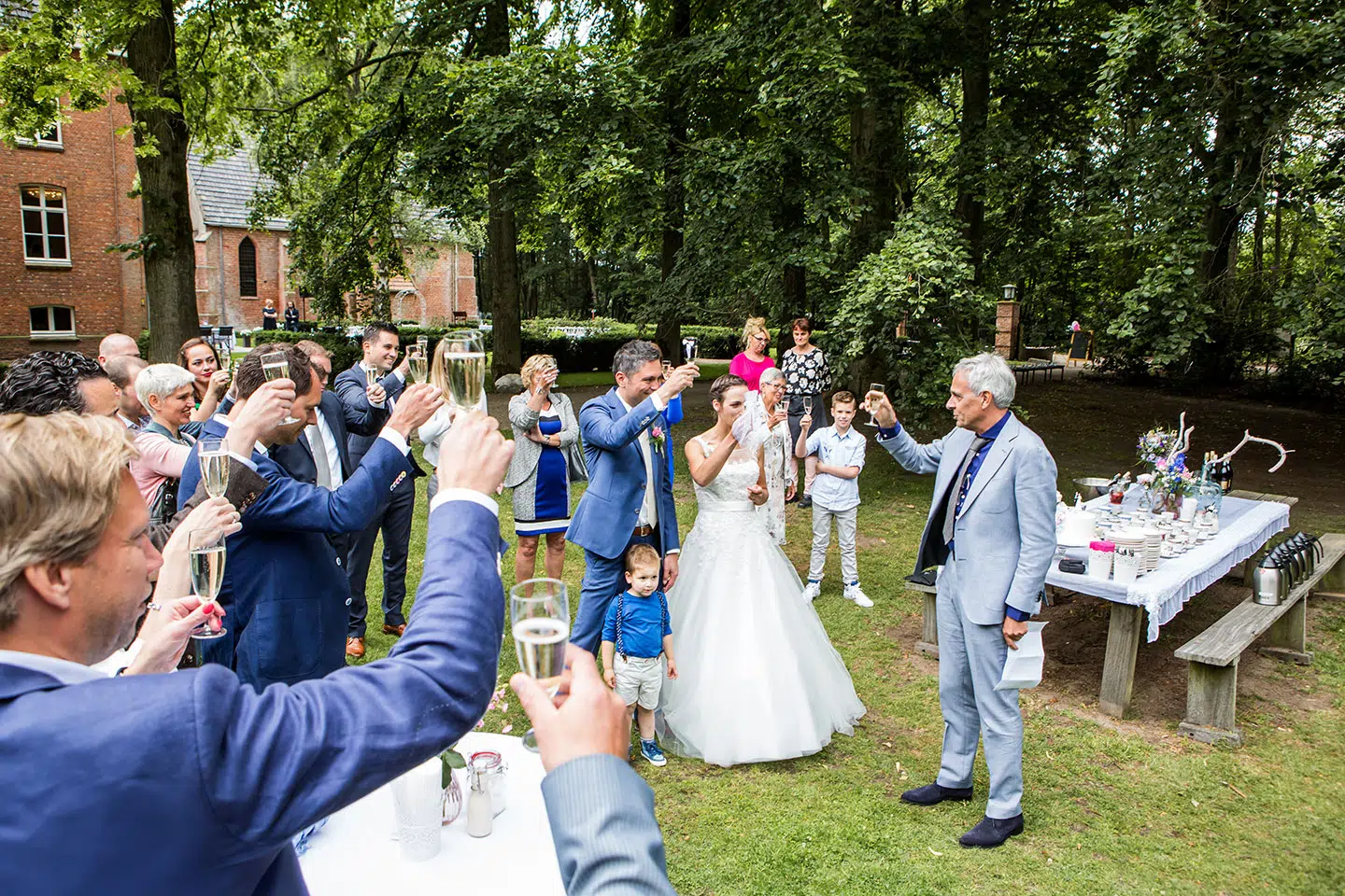 Bruidspaar proost met gasten tijdens hun bruiloft bij Klooster Nieuwkerk