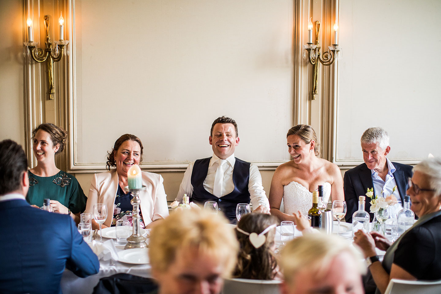 Bruidspaar met hun gasten aan tafel tijdens een bruiloft bij Landgoed Waterland